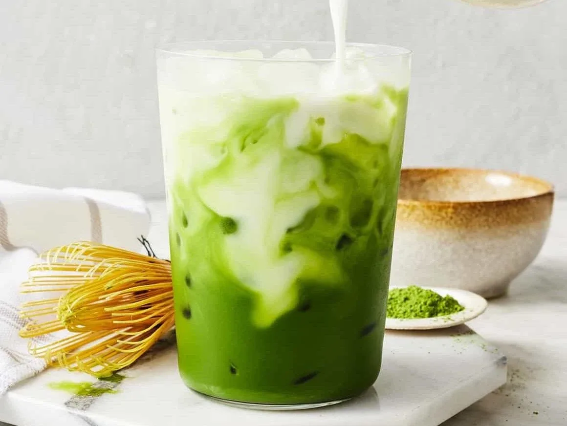 Iced matcha latte with a bamboo whisk